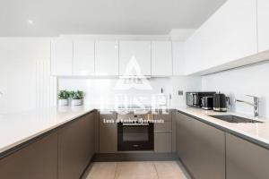 una cucina con armadi bianchi e piano cottura di Modern, Stylish PENTHOUSE Apartment next to Wembley Stadium! a Londra
