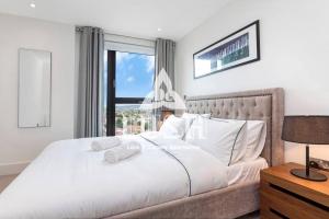 a bedroom with a large white bed with a window at Modern, Stylish PENTHOUSE Apartment next to Wembley Stadium! in London