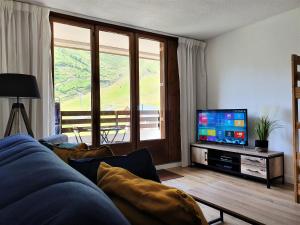 a living room with a couch and a flat screen tv at Appartement à la montagne avec vue Imprenable in Gouaux-de-Larboust