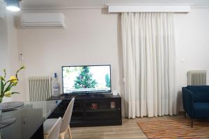 Larissa Downtown Apartment With Parking في لاريسا: غرفة معيشة مع تلفزيون وطاولة طعام