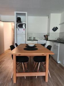 una cocina con una mesa de madera con sillas alrededor. en Appartement à la montagne avec vue Imprenable, en Gouaux-de-Larboust