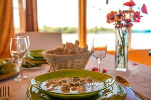 a table with a bowl of food and wine glasses at Hotel Plutitor Kingfisher in Uzlina