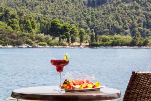 a glass of wine and fruit on a table by the water at Blue Green Bay in Panormos Skopelos