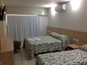 a hotel room with two beds and a couch at Itumbiara Palace Hotel in Itumbiara