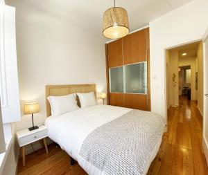 Schlafzimmer mit einem großen weißen Bett mit einem Kopfteil aus Holz in der Unterkunft El Patio 79 in Lissabon