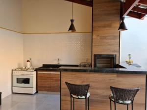 a kitchen with a stove and two chairs in it at Recanto H & E in Olímpia