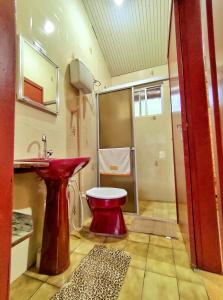 W łazience znajduje się czerwona toaleta i umywalka. w obiekcie Suíte Rústica w mieście Florianópolis