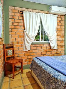 1 dormitorio con pared de ladrillo, cama y silla en Suíte Rústica, en Florianópolis