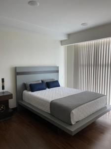 a bedroom with a large bed with blue pillows at Lovely Apartment near Costa Rica airport in Heredia