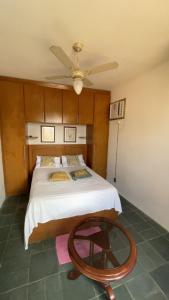 a bedroom with a bed with a ceiling fan and a table at Pousada Buganvilia in Bombinhas