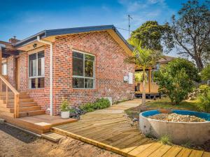 uma casa de tijolos com um deque de madeira em frente em Rhyll Relaxer em Rhyll