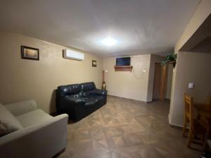 a living room with a black leather couch and a table at Cabaña el Pino 1 in Creel