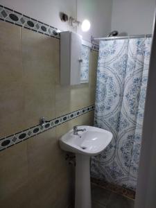 a bathroom with a sink and a shower curtain at Alojamiento Barrio Sur in Colonia del Sacramento +25 photos