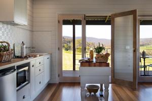 a kitchen with white cabinets and a sliding glass door at Fellcroft Farmstay in Cobaw