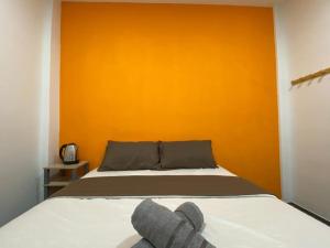 a bedroom with a bed with an orange wall at YipStay in Gopeng