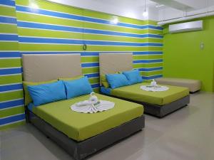 マニラにあるYuj Inn Pasayの緑と青のストライプが入った部屋にベッドが2つある