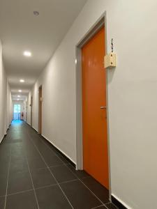 an empty hallway with an orange door and a tile floor at YipStay in Gopeng