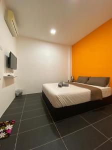 a bedroom with a bed with an orange wall at YipStay in Gopeng