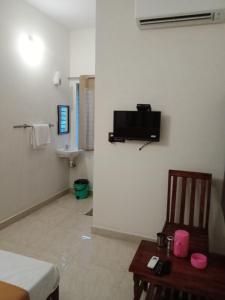 a room with a tv on the wall and a table at Harsha Haritha Residency in Cuddalore