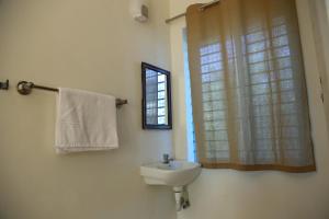 a white bathroom with a sink and a window at Harsha Haritha Residency in Cuddalore
