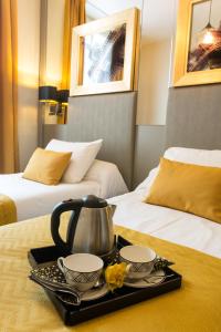uma bandeja com uma chaleira e 2 chávenas numa cama em Pratic Hotel em Paris