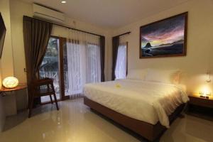 una camera da letto con un grande letto bianco e una finestra di Onesouth Boutique Hotel Pulau merah a Banyuwangi Altre 11 foto