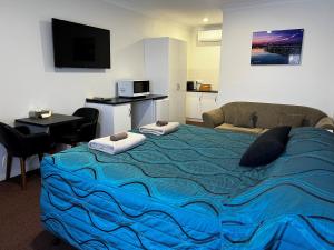 a bedroom with a large bed with a blue blanket at Augusta Courtyard Motel in Port Augusta