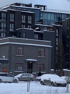 zwei Autos, die vor einem Gebäude im Schnee geparkt sind in der Unterkunft Emily in Riga