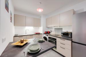a kitchen with white cabinets and a table with plates on it at Le Concert - Beautiful appartment with garage for 4 people near beach in Annecy