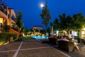 a group of people sitting in chairs near a pool at night at Rigas Hotel Skopelos by GHH in Skopelos Town