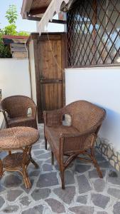 zwei Korbstühle und eine Bank auf einer Terrasse in der Unterkunft villino 4 posti letto con cucina a 30mt dal mare in Fiumicino