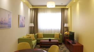 Al Riyadh Hotel Apartments في أبوظبي: غرفة معيشة مع أريكة خضراء ونافذة