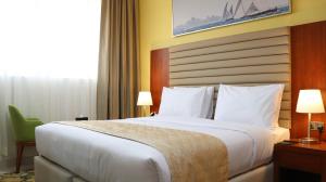 Al Riyadh Hotel Apartments في أبوظبي: غرفة فندقية بسرير كبير ونافذة