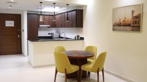 a kitchen with a wooden table and yellow chairs at Al Riyadh Hotel Apartments in Abu Dhabi