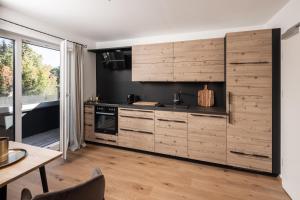 a kitchen with wooden cabinets and a table and a dining room at Moxn Apartment Lungau - Small Penthouse mit Terrasse in Mauterndorf