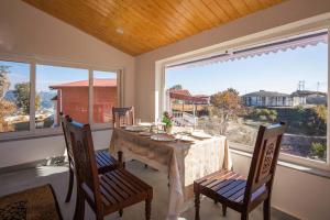 a dining room with a table and chairs and windows at StayVista at Albert Estate in Mussoorie