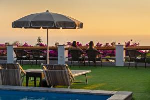 people sitting in chairs under an umbrella by a pool at Hotel Il Girasole in Anacapri