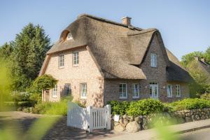 a house with a thatched roof and a white fence at Ferienhaus Koellers Hus in Sankt Peter-Ording