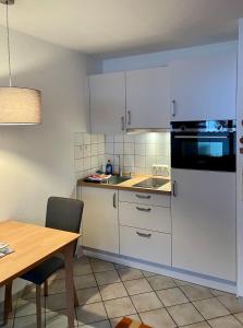 a kitchen with white cabinets and a wooden table at Ferienwohnung Niklas inklusive Bad Hindelang Plus in Bad Hindelang
