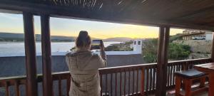 a woman taking a picture of the sunset from a balcony at Luxury Breede River View at Witsand- 300B Self-Catering Apartment in Witsand
