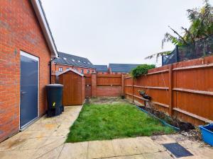einen Hinterhof mit einem Zaun und einem Garten mit Gras in der Unterkunft Cheerful 5-BDR/3-BATH House w/ Free Parking in Reading
