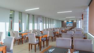 un comedor con mesas, sillas y ventanas en Creta Verano Hotel, en Malia