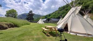 a tent with a table and a grill in a field at Tipi nature grand confort in Gavarnie