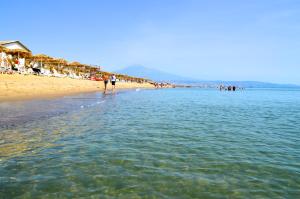 a beach with people standing in the water at Villaggio Turistico Europeo in Catania