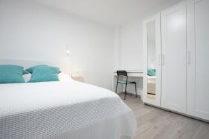 a white bedroom with a bed and a desk at Apartmani Dora in Požega