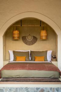 a bedroom with a bed with orange pillows and two lights at Drop In Surf Lodge in Kuta Lombok