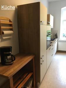 Una cocina con una mesa de madera y un refrigerador. en Ferienwohnung RIENA, en Riesa