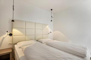 sypialnia z 2 łóżkami i białą ścianą w obiekcie Apartment Dui Residence Bun Ste w mieście San Vigilio di Marebbe