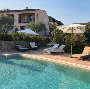 a swimming pool with chairs and umbrellas next to a house at Lone Star House in Sainte-Maxime