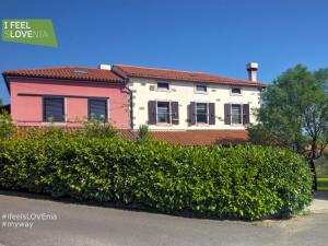 a pink and white house behind a hedge at Apartments Spirit of Istria in Truške
